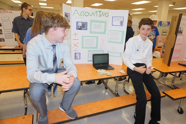 two boys sitting in front of a tri board